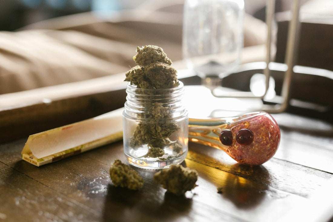 Cannabis buds in and around a small glass jar