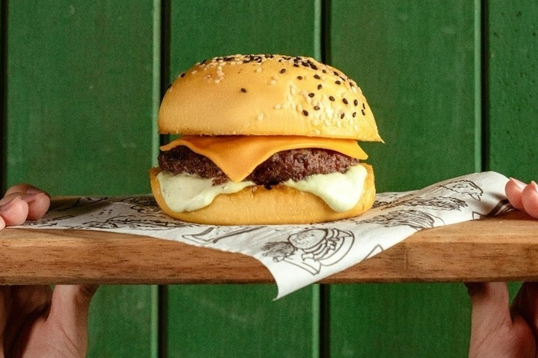 Person holding a cheeseburger on a plate