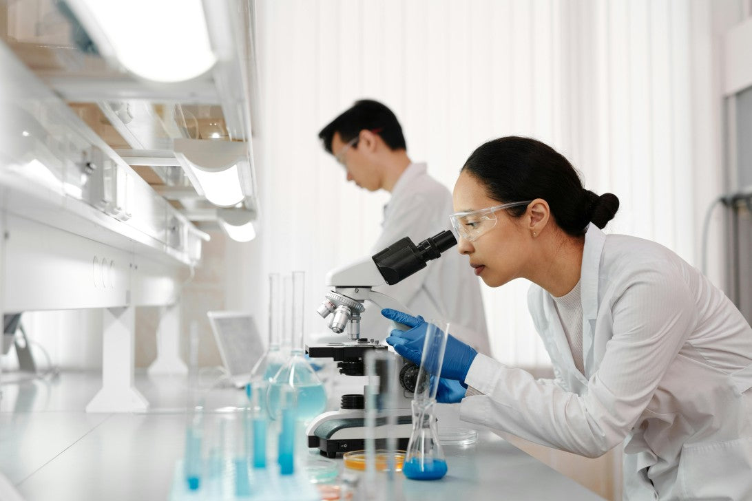 Scientists in labcoats analyzing specimens under a microscope