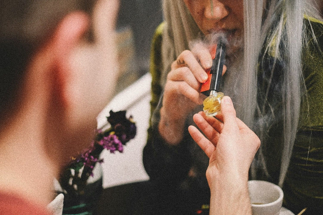 A woman using a dab tool with weed concentrates being held by a man