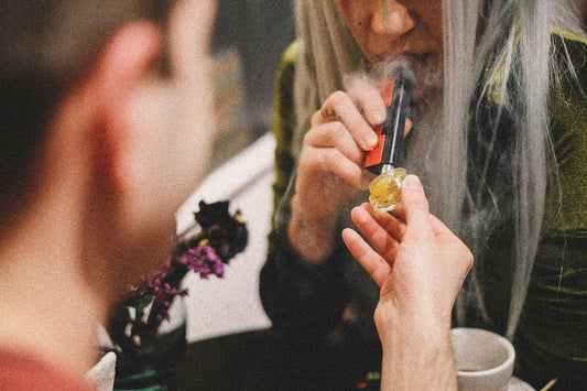 A woman using a dab tool with weed concentrates being held by a man