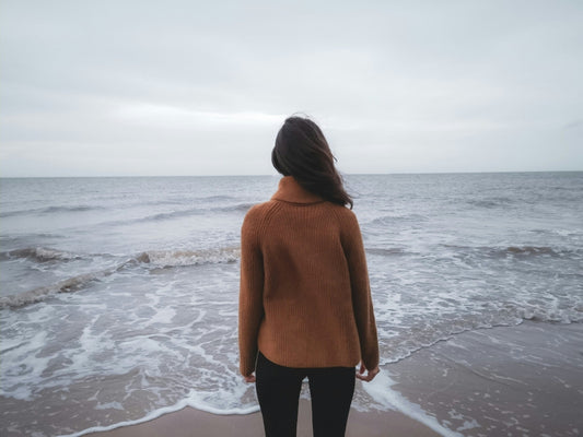 Woman looking out at the ocean on a cloudy day