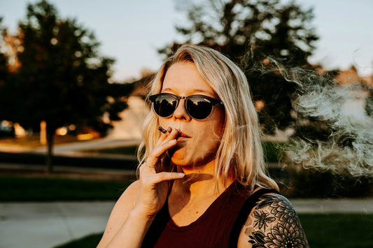 Woman smoking a joint outside in sunglasses