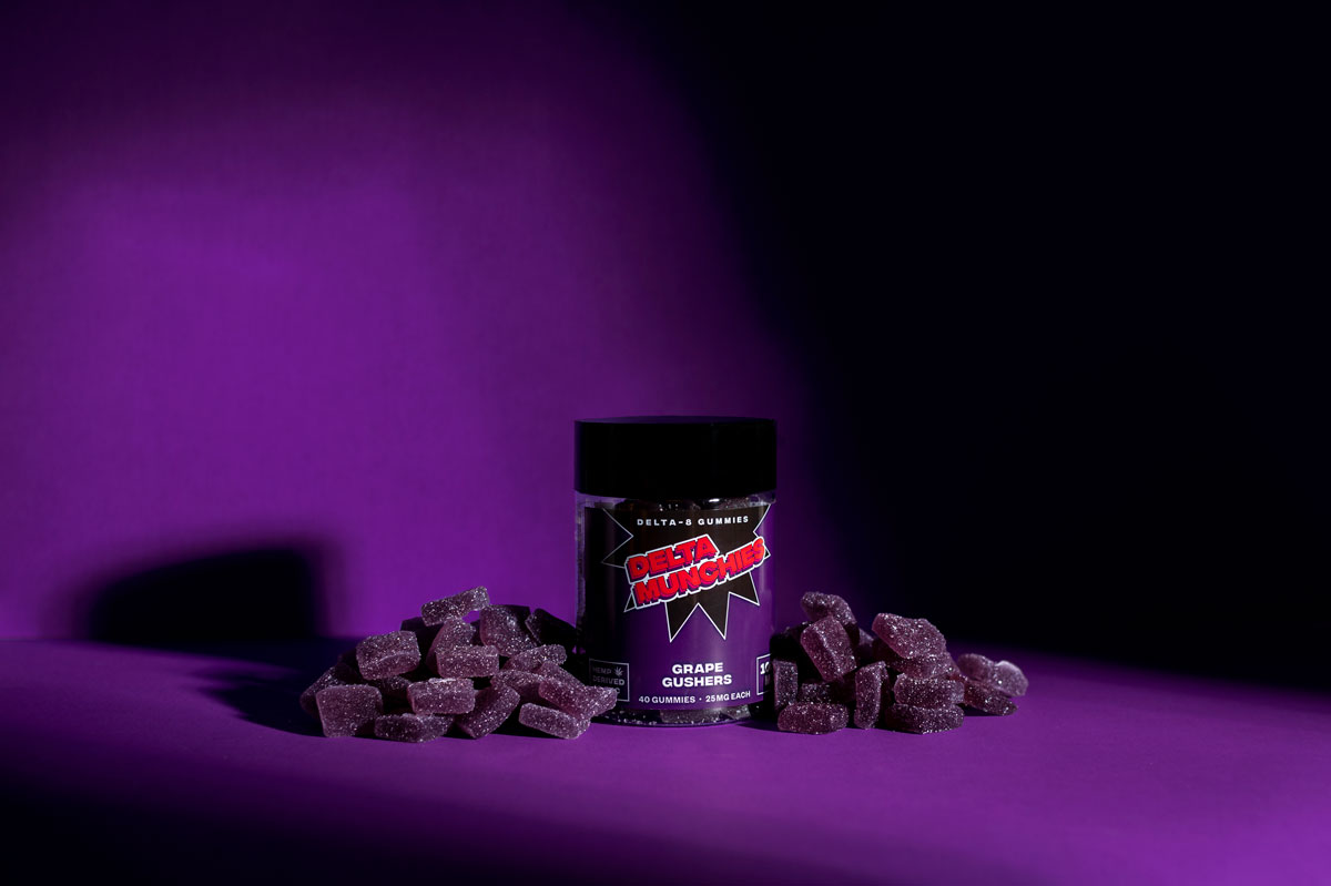 Delta Munchies Grape Gushers 1000mg delta 8 thc gummies on a purple background with grapes
