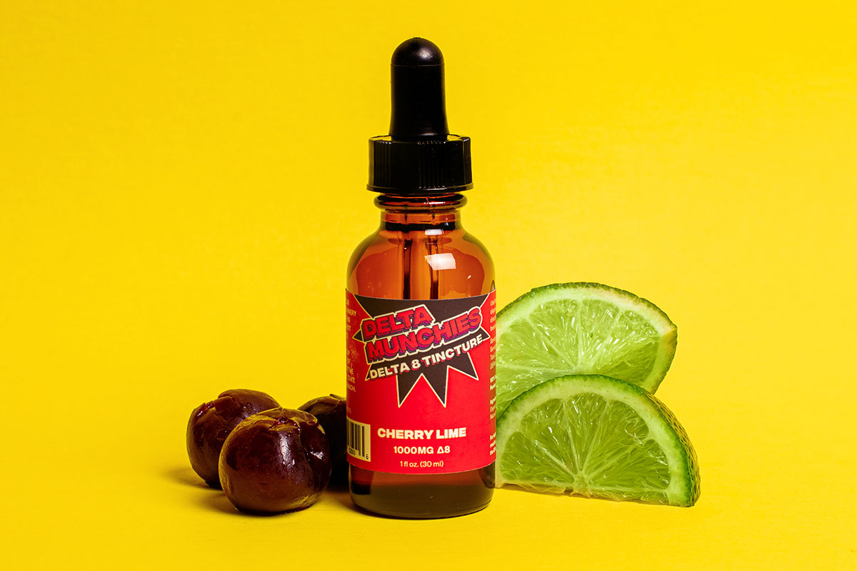 Delta Munchies Cherry Lime delta 8 tincture sitting next to cherries and slices of lime.