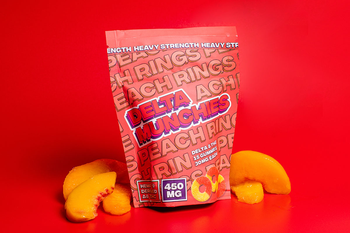 Bag of Delta Munchies' Peach Rings nect to peach slices on a red set.