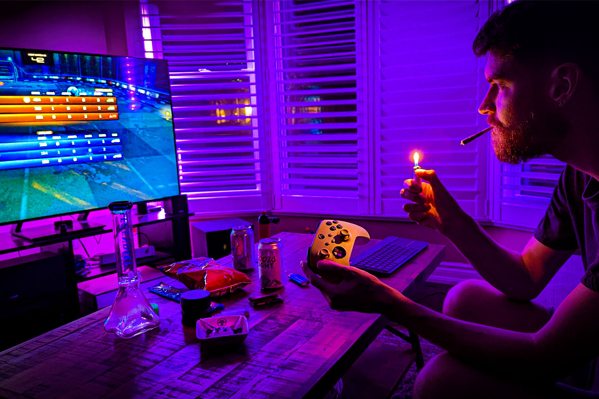 Man lights a joint while playing a video game ina living room.