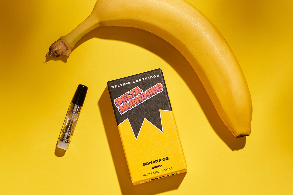 Delta Munchies' Banana OG delta 8 THC vape cartridge next to its box and a yellow banana.