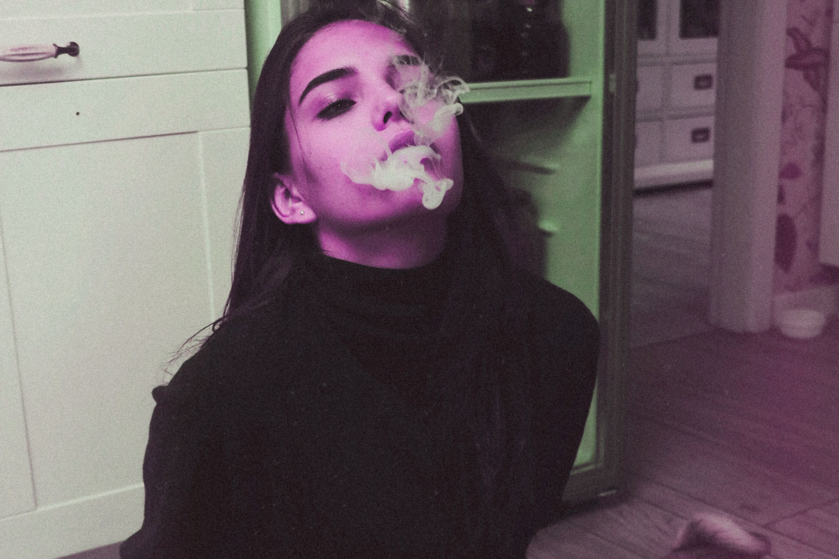 Woman blowing smoke performing a smoke trick.