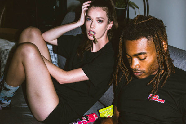 Man and woman sitting on a couch smoking a blunt.