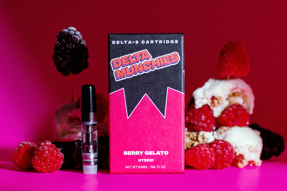 Delta Munchies' Berry Gelato delta 8 vape cartridge on a table next to mixed ebrries and ice cream.
