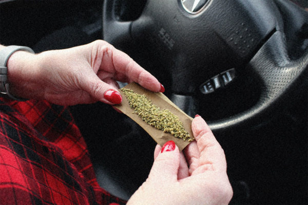 Woman rolling a joint in a car.