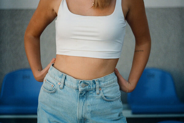 Woman wearing a white crop top and jeans. 