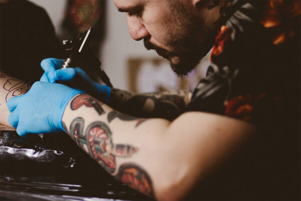 Tattoo artist tattoing a mans neck.