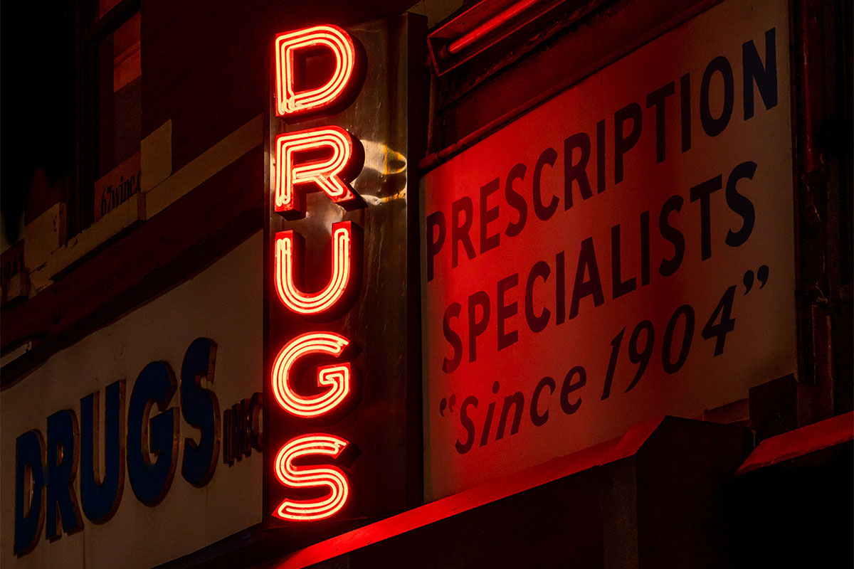 Vertical neon sign that reads "Drugs".