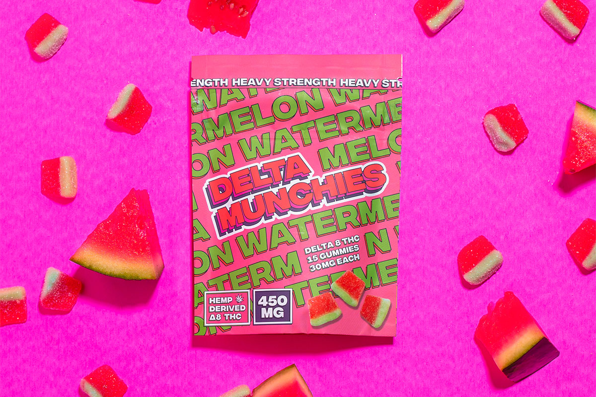 A pack of 450mg delta-8 THC gummies sits on a pink background surrounded by juicy watermelon slices and some gummies