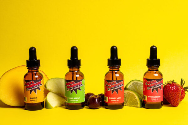 Four 1000mg Delta 8 tinctures - Mango, Sour Apple, Cherry Lime, and Strawberry - with fruit on yellow background