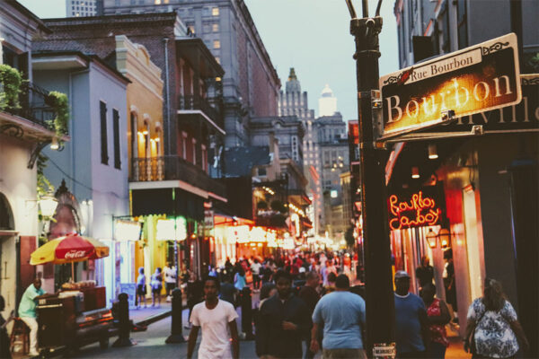 Lively evening on Bourbon Street, Louisiana: bustling crowd, vibrant shops, glowing lights