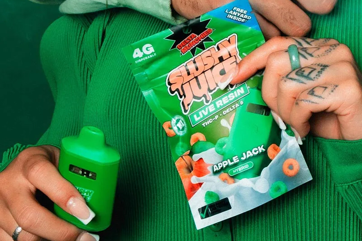 A man holding a pack of SLUSHY JUICE live resin with Apple Jack flavor in one hand and a green bottle in the other